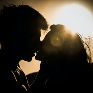 man and woman kissing under the sun