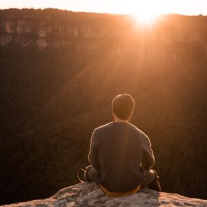 man in bonnet sitting on top of mountain